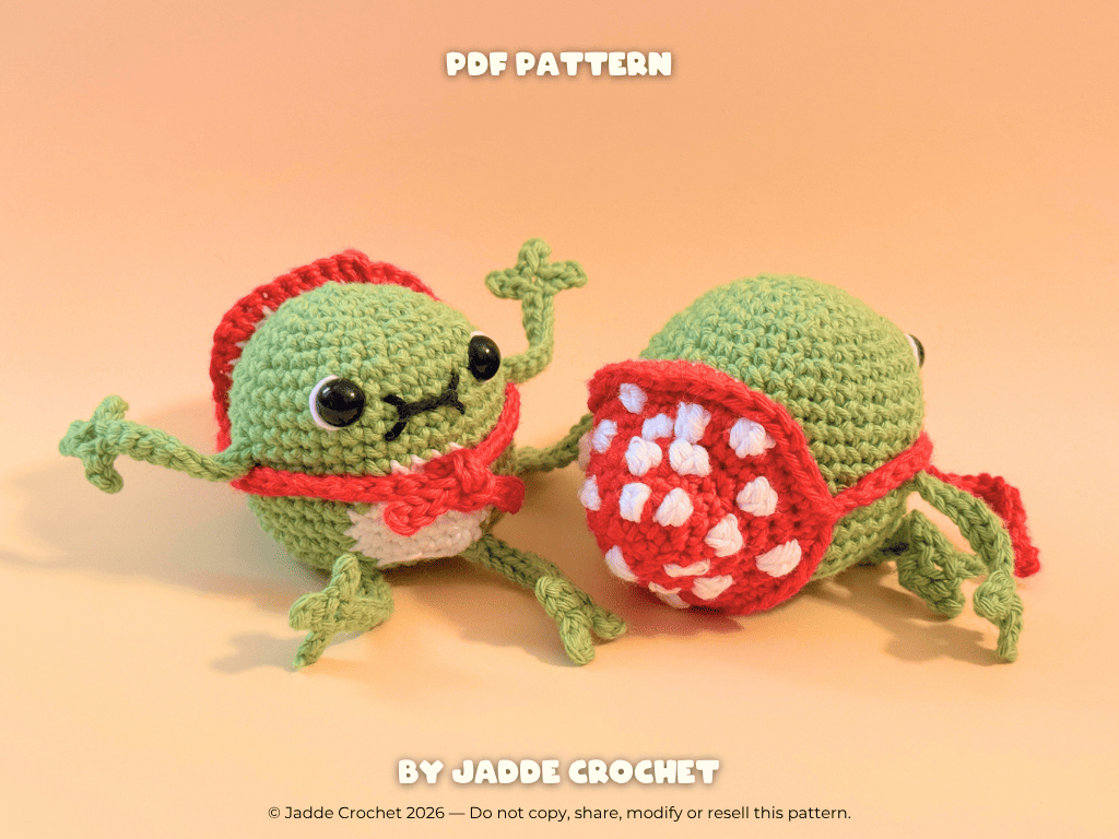 Two green crochet frogs with amanita mushroom hats on a beige background, featuring 'Jadde Crochet' branding.
