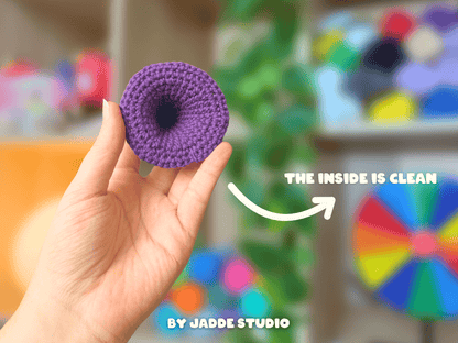 A hand holds a small purple crocheted donut-shaped item against a blurred colorful background. White text on the image reads 'THE INSIDE IS CLEAN' with an arrow pointing to the item, and 'BY JADDE STUDIO' appears at the bottom.