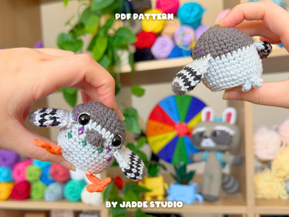 Two hands holding crocheted bird amigurumi toys in front of a colorful yarn and plush display. Text overlays read 'PDF PATTERN' and 'BY JADDE STUDIO'.