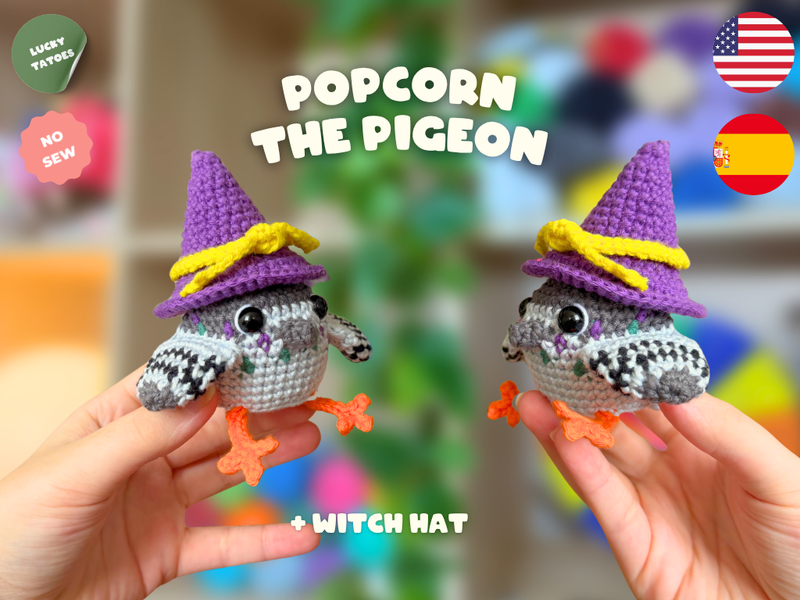 Two hands holding small crocheted pigeon toys wearing purple witch hats with yellow bows, with text reading 'POPCORN THE PIGEON' and 'WITCH HAT' on a colorful blurred background. Flags for USA and Spain and badges for 'Lucky Tattoos' and 'No Sew' appear in the corners.