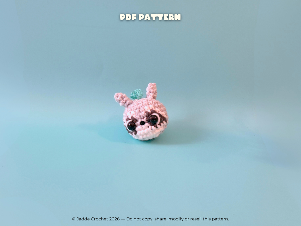 Crocheted raccoon with black eyes on a light blue background, labeled 'PDF Pattern'.