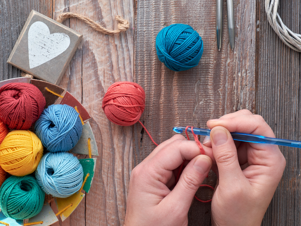 Colorful yarn balls and a crochet hook on a wooden surface
